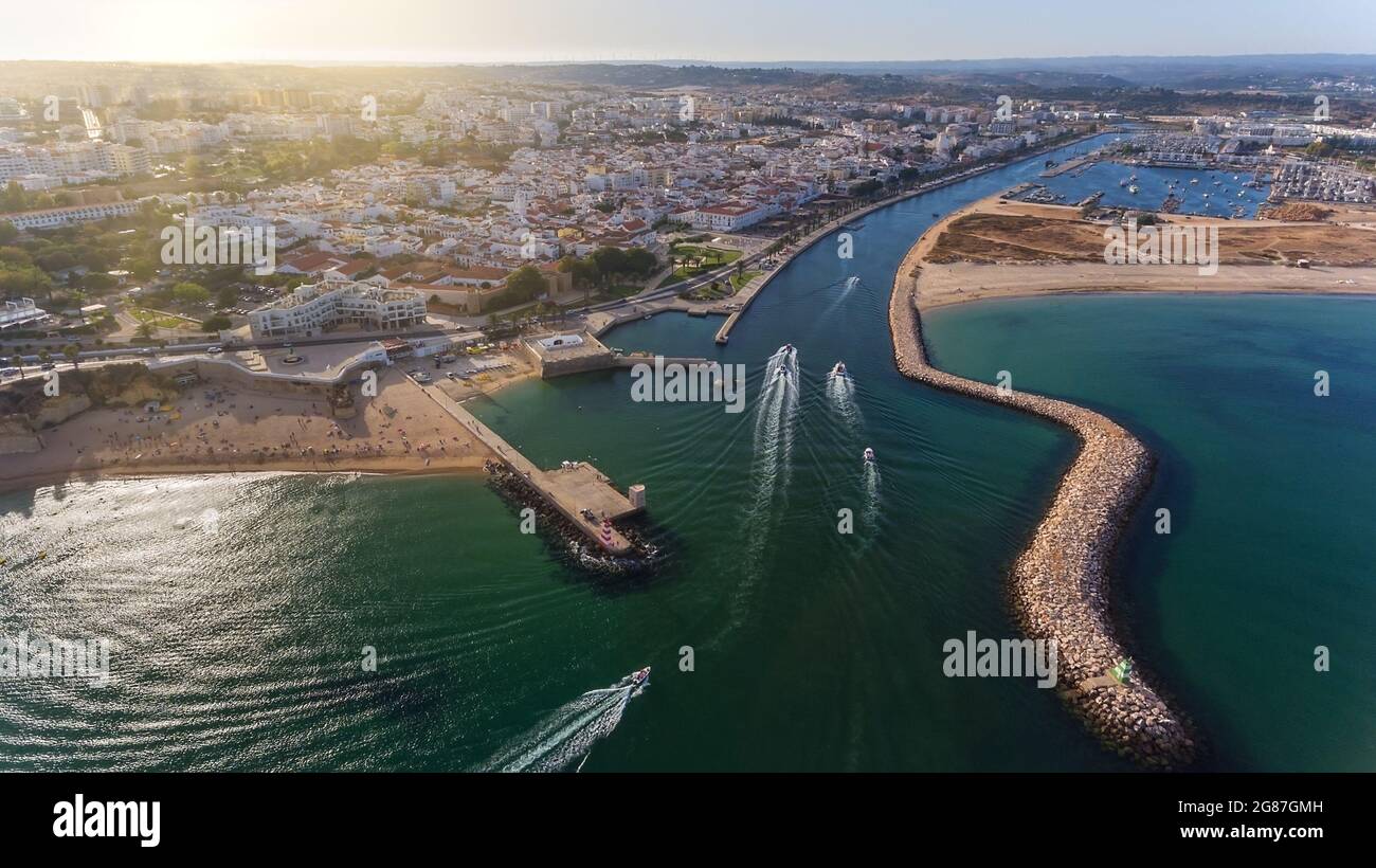 Aerial view from the sky of the Portuguese coastline of the Algarve zone of Lagos city. Boats and ships are moving in the direction of the port. Stock Photo