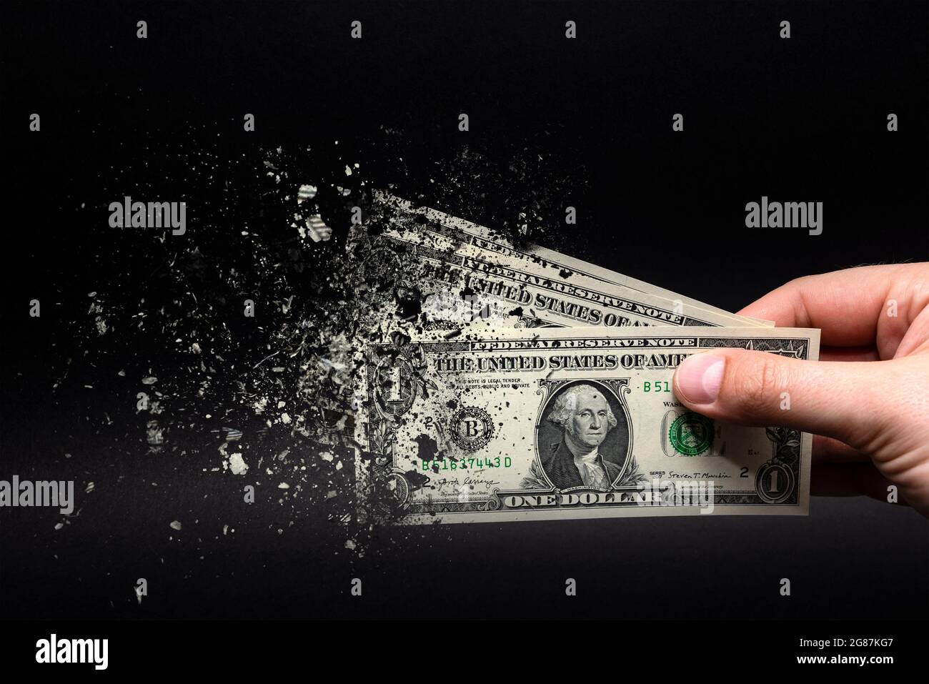 Spend money, spend all your money illiterately. The dollar bill turns to ash, dissolves against a black background. Place for text. Stock Photo