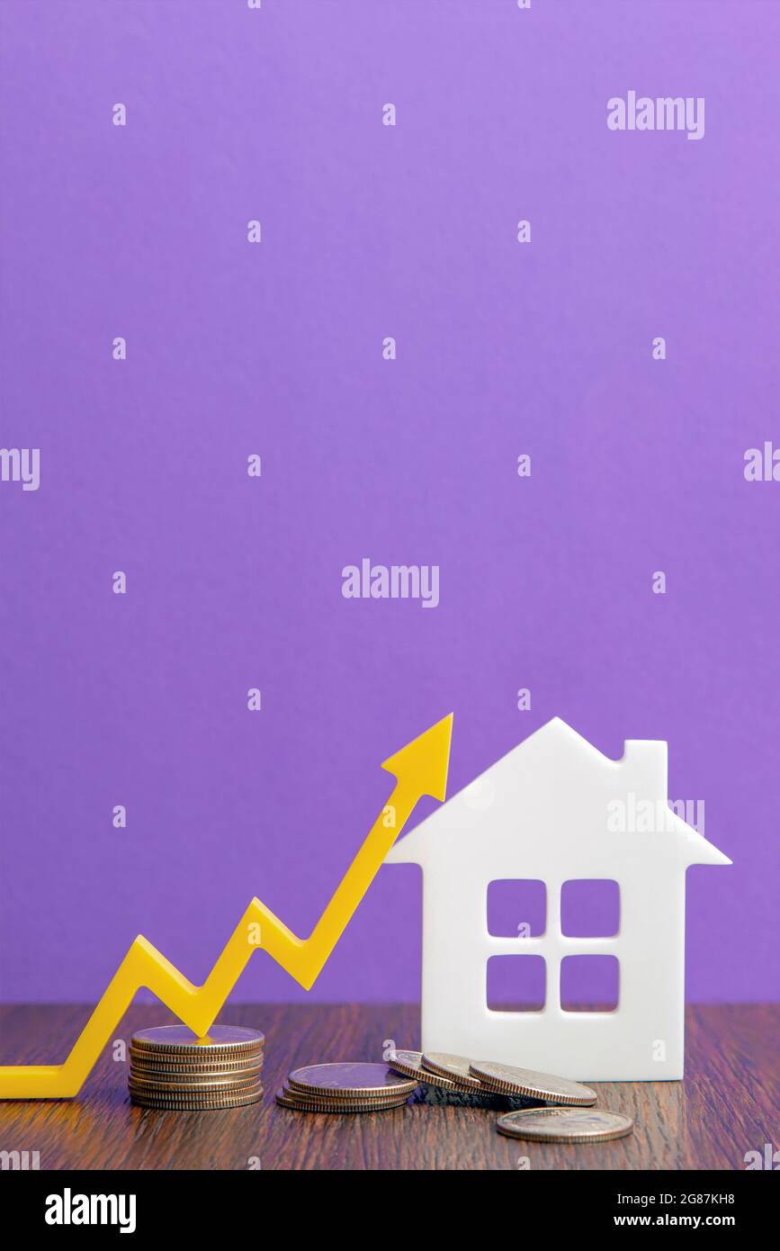 Real estate market, graph, up arrow. House construction model and a stack of coins. The concept of inflation, economic growth, the price of insurance Stock Photo