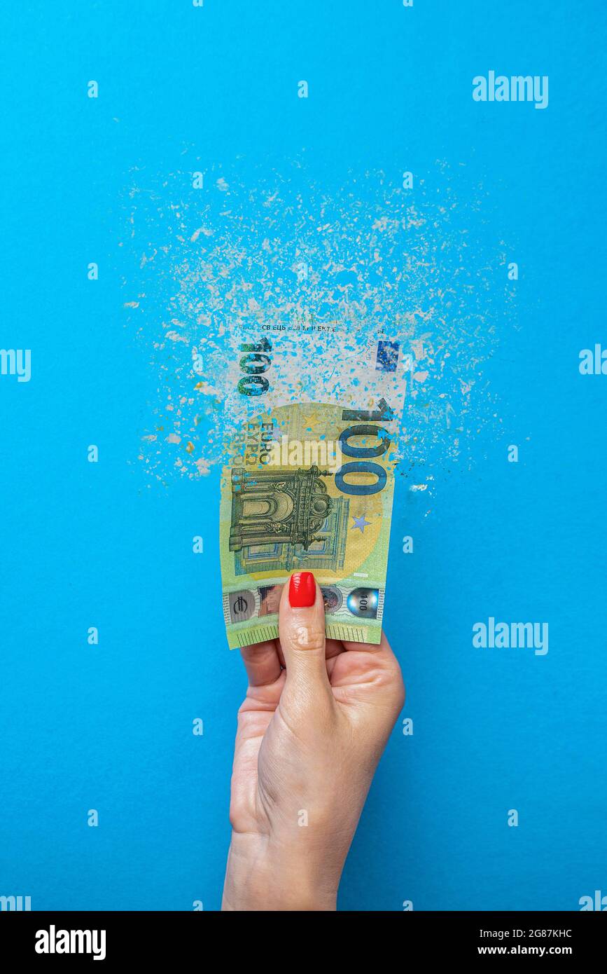 Euro inflation. Inflation in Europe, hyperinflation. Banner with blue background. One hundred euro banknote sprayed in the hand of a man on a blue Stock Photo