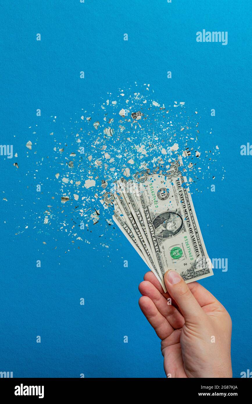Devaluation of money. Printing money leads to inflation. Decrease in the value of the American currency, dollar. Dollar bill breaks up into particles Stock Photo