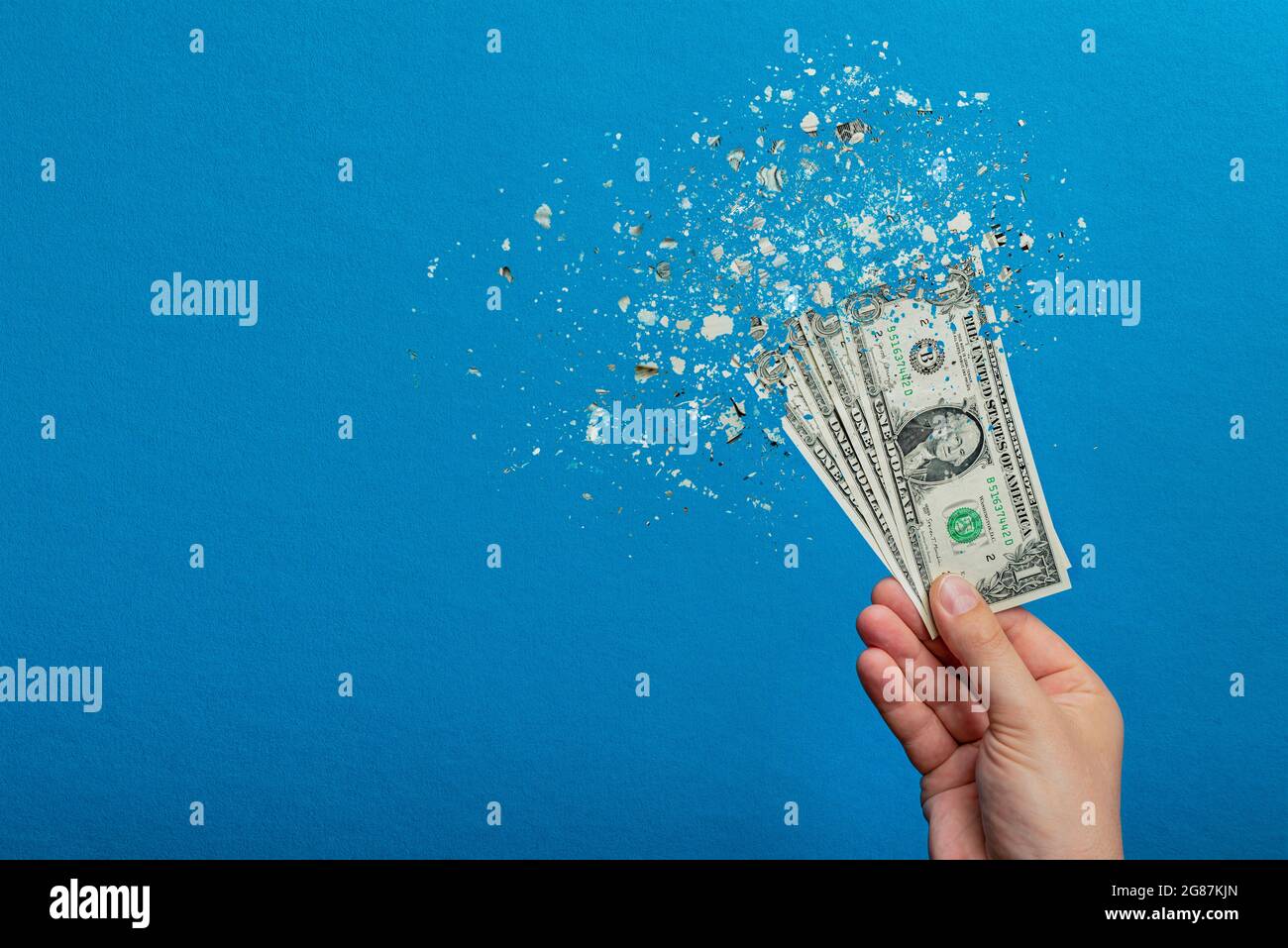 Inflation, dollar hyper inflation. Banner with blue background. One dollar bill is sprayed in the hand of a man on a blue background. Price rise Stock Photo