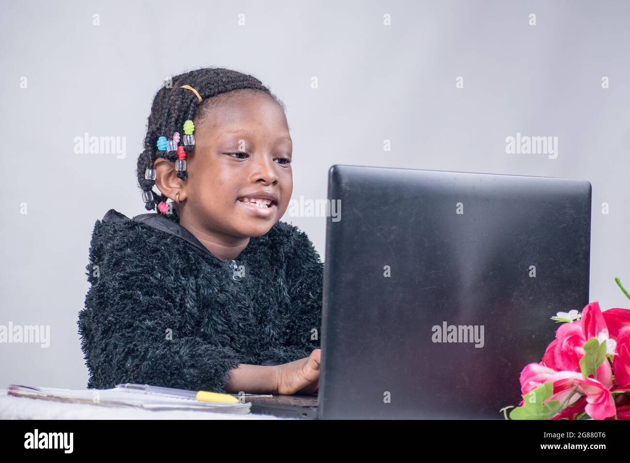 African girl child typing, studying, learning, and researching for excellence in her education with a laptop Stock Photo