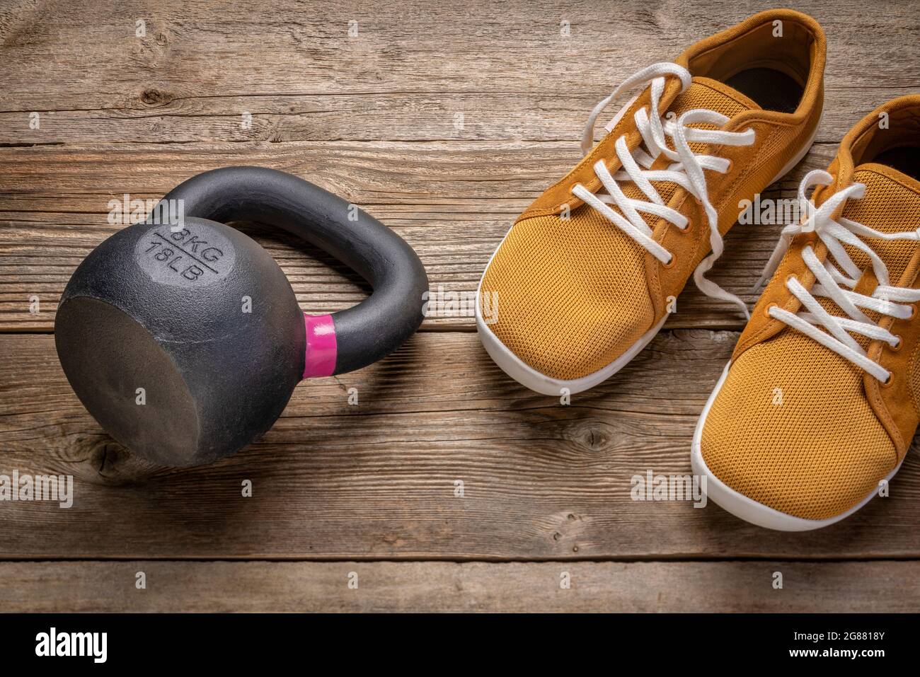 small iron kettlebell with barefoot sneakers on a rustic wooden deck,  fitness concept Stock Photo - Alamy