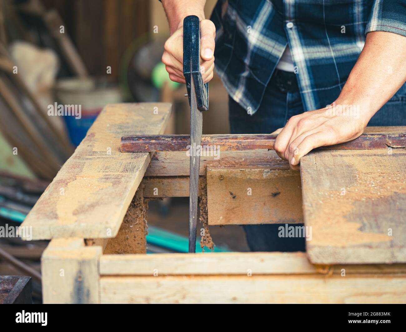 The carpenter using a hand saw for woodworking in his workshop Stock Photo