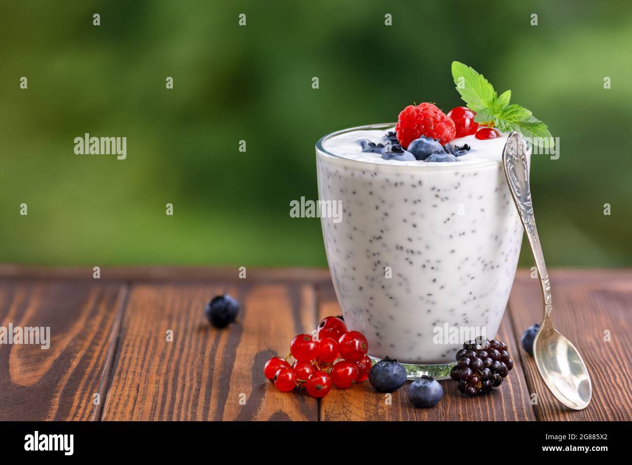 chia pudding with yogurt and fresh berries in glass on table outdoors Stock Photo