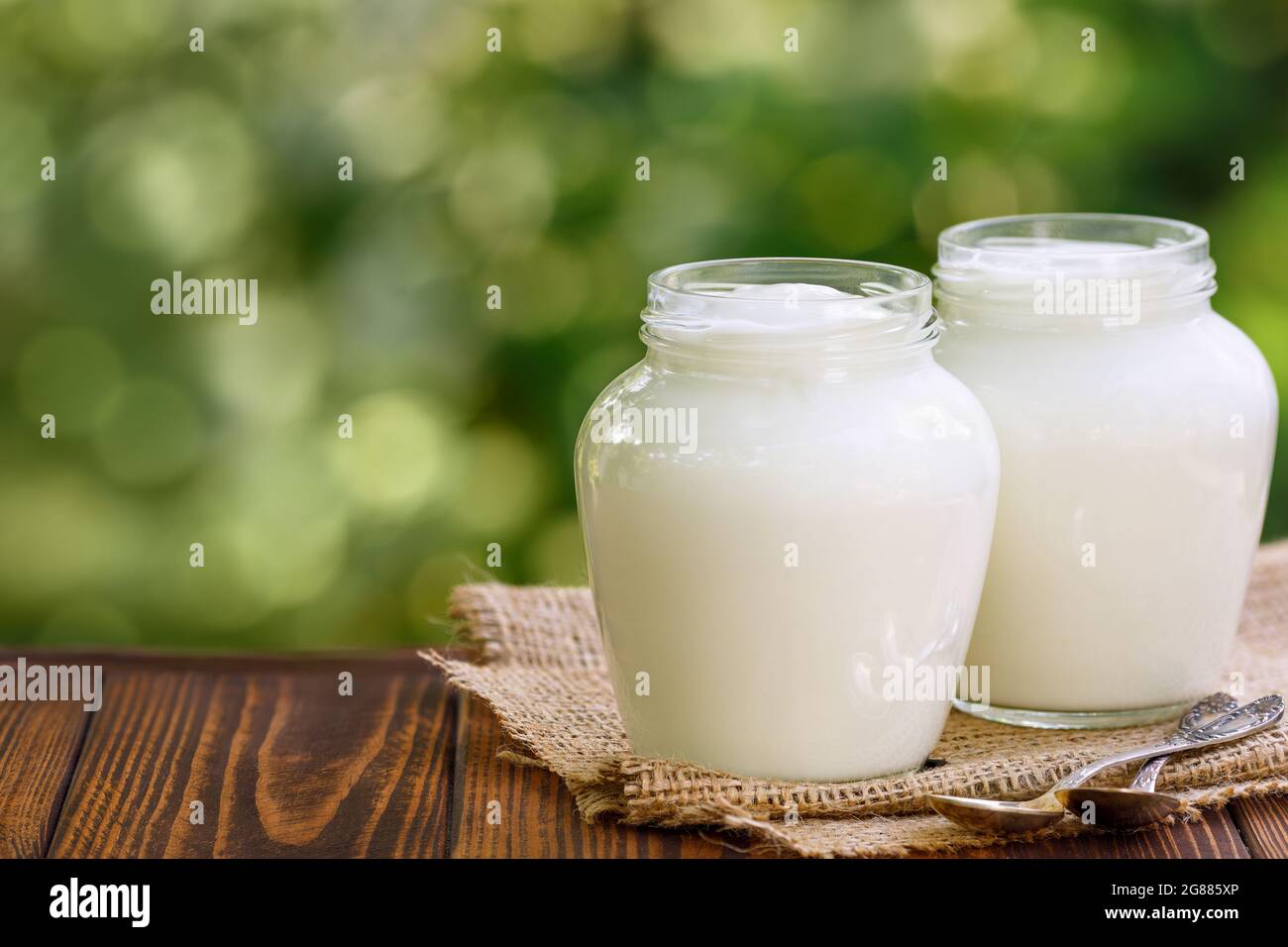 greek yogurt in two glass jars on table outdoors Stock Photo