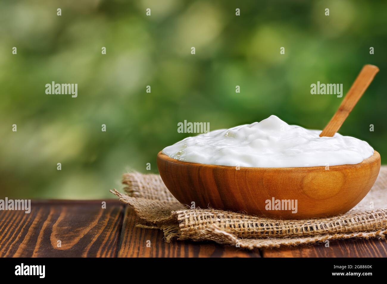 sour cream in wooden bowl on table outdoors Stock Photo