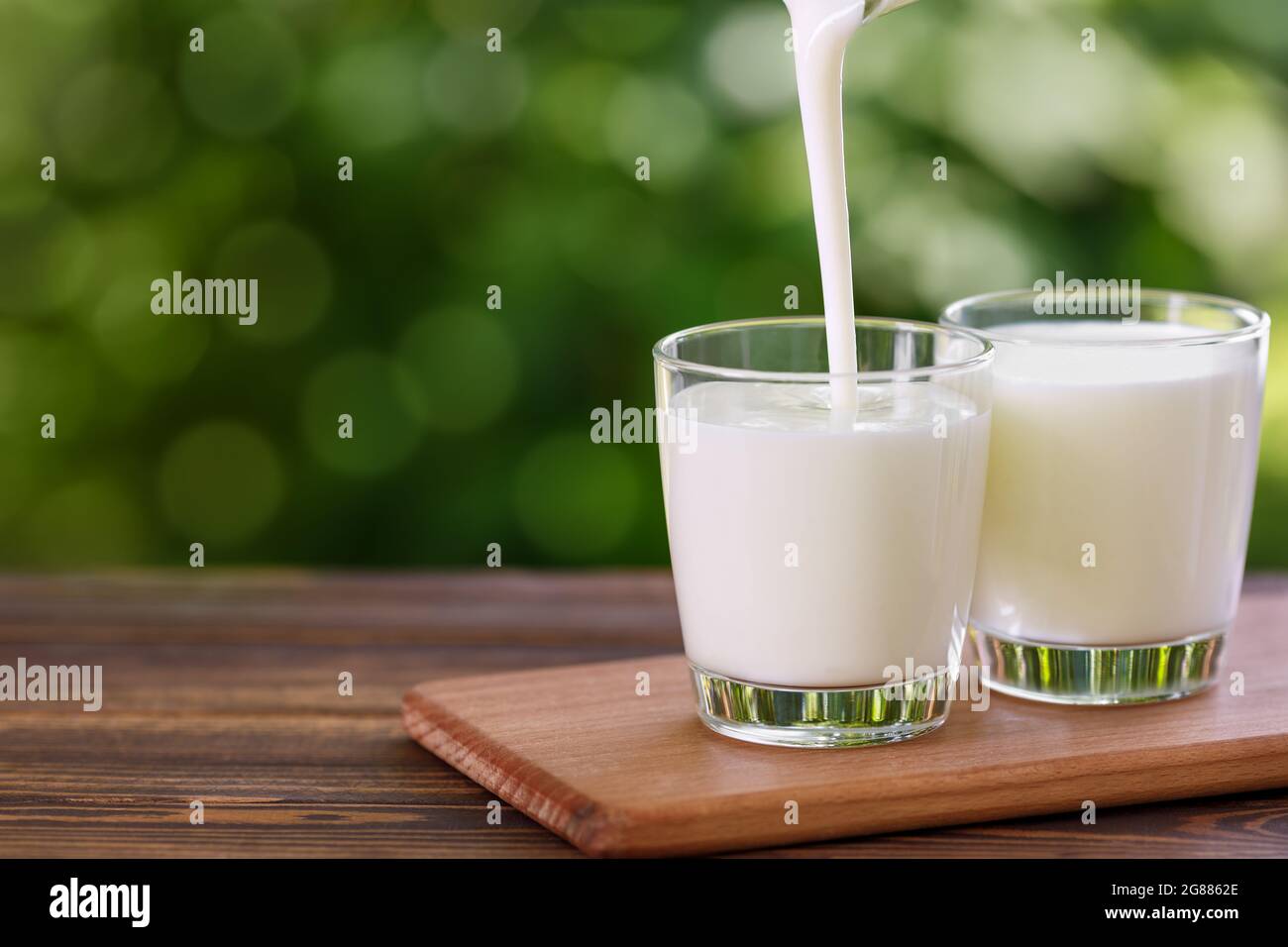 yogurt pouring into glass on wooden table Stock Photo