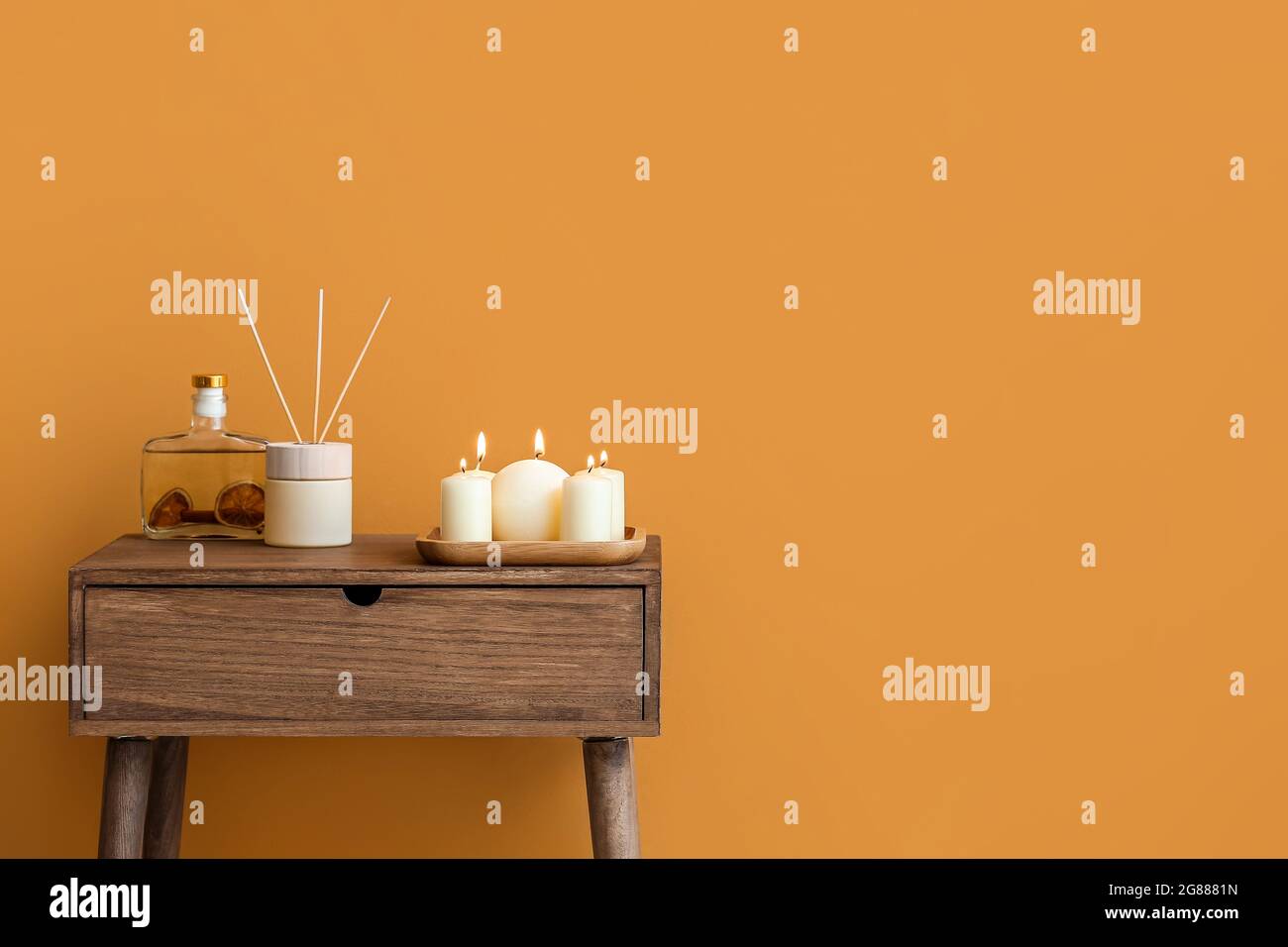 Burning candles and reed diffuser on table near color wall Stock Photo ...