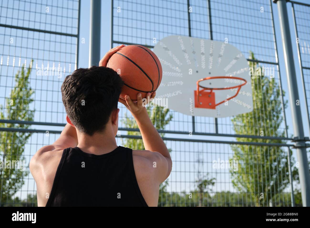 Back view of a basketball player throwing the ball to the basket