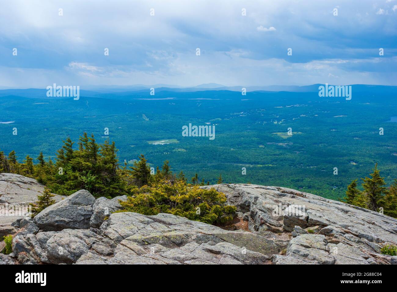 Western view from Mt. Kearsarge summit towards Lake Sunapee and Mt. Ascutney. Rocky granite outcrop and stunted spruce trees. Distant peaks and ridges Stock Photo