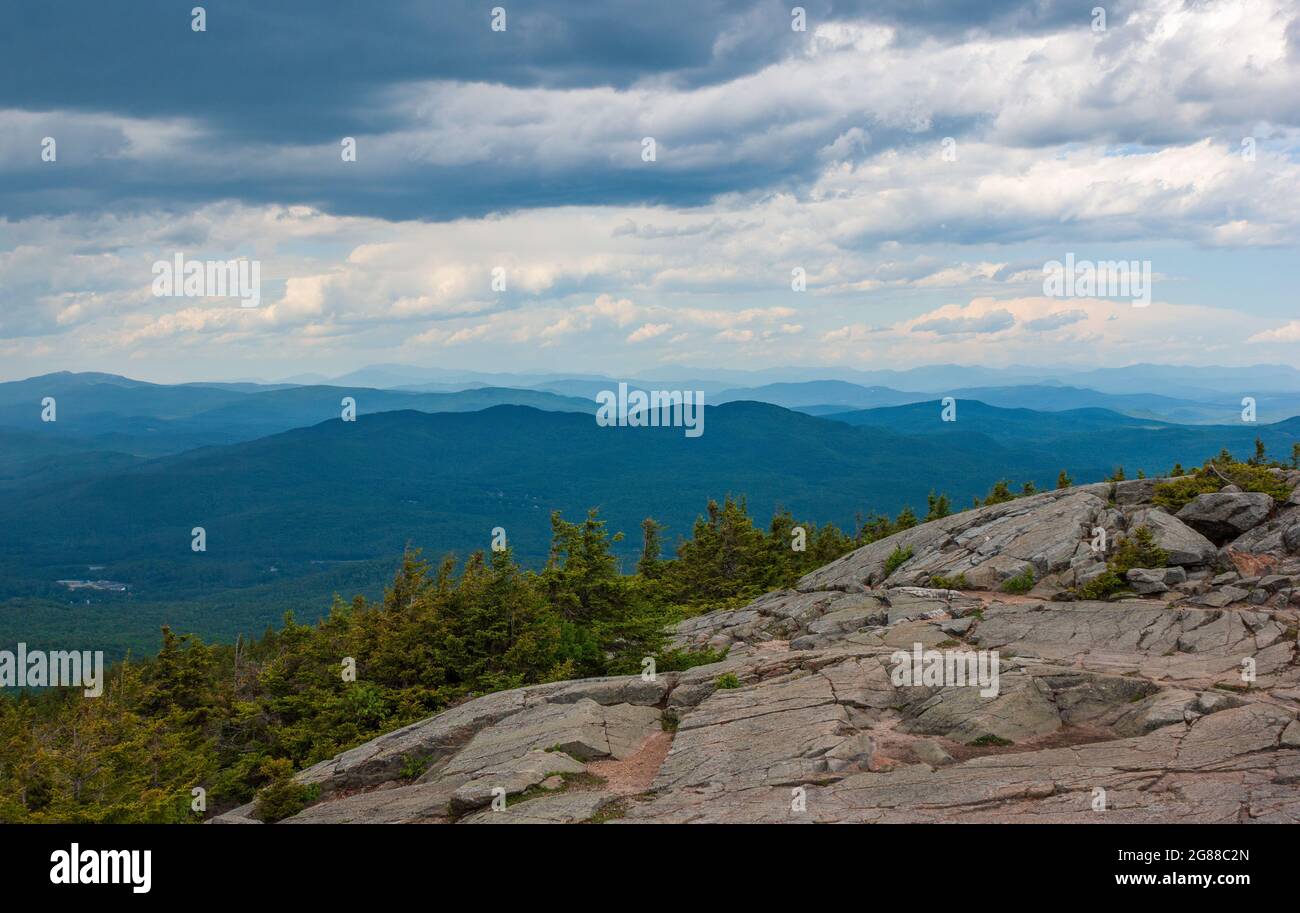 Northern view from Mt. Kearsarge summit towards Ragged Mountain.  Granite outcrop and stunted spruce trees. Distant White Mountains peaks and ridges. Stock Photo