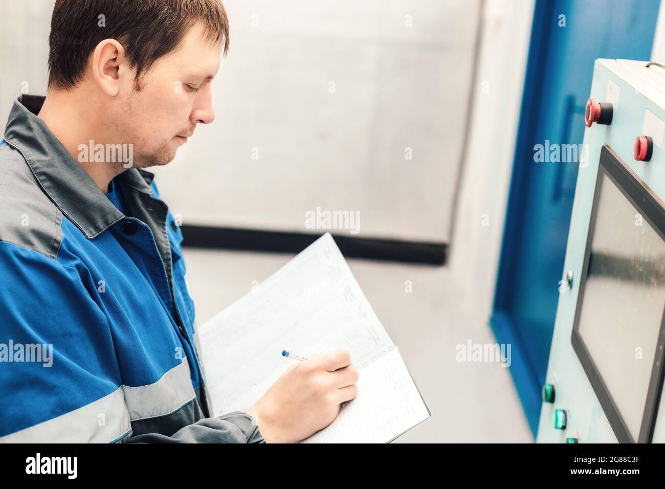 Engineer, worker registers readings of sensors and pressure gauges. Control of water supply and heating system. Checking the equipment before the start of the heating season Stock Photo