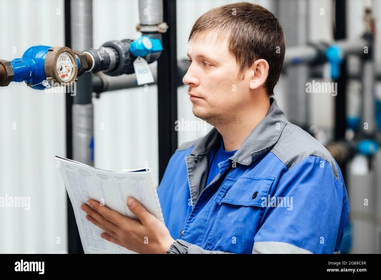 Engineer, worker registers readings of sensors and pressure gauges. Control of water supply and heating system. Checking the equipment before the start of the heating season Stock Photo