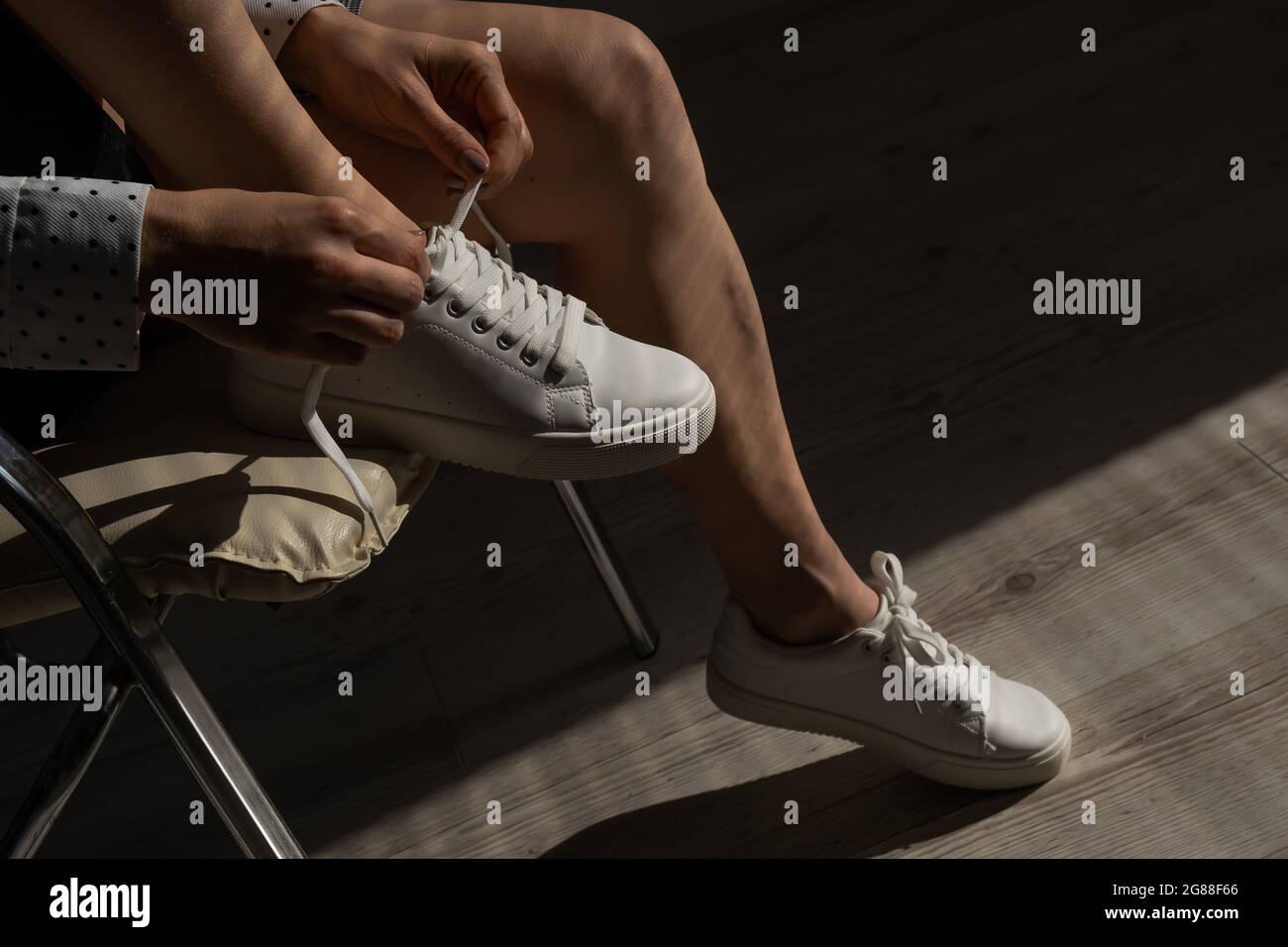 Woman put on new white leather sneakers Stock Photo - Alamy