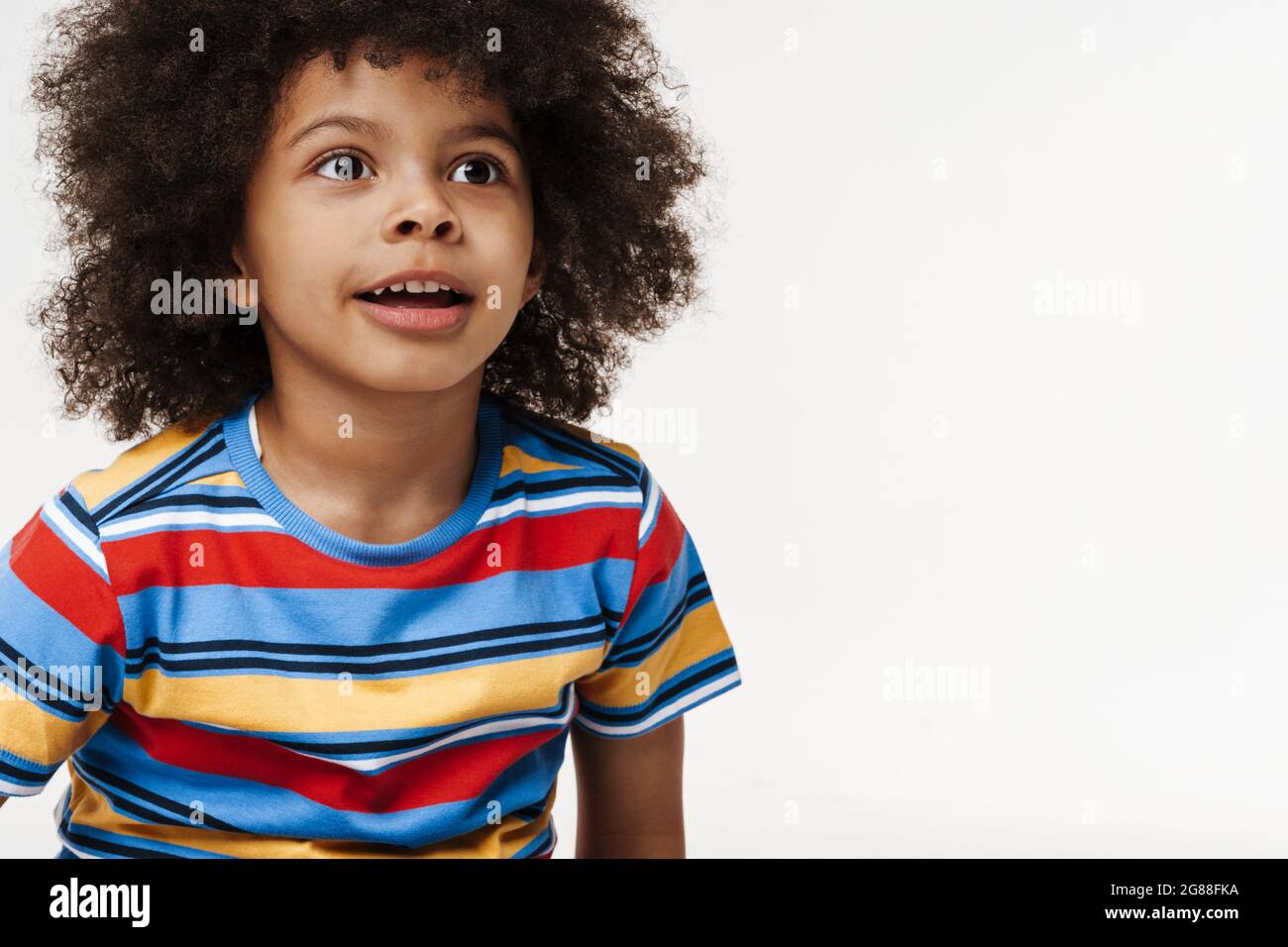 Smiling little african boy in everyday clothes over wall background