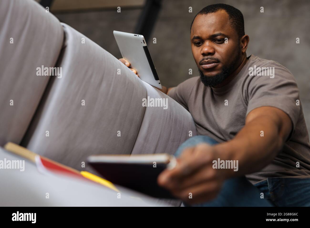 Black unshaven man using tablet computer while working at home Stock Photo