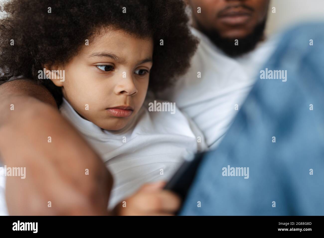 Black father and son using tablet computer while resting together at home Stock Photo