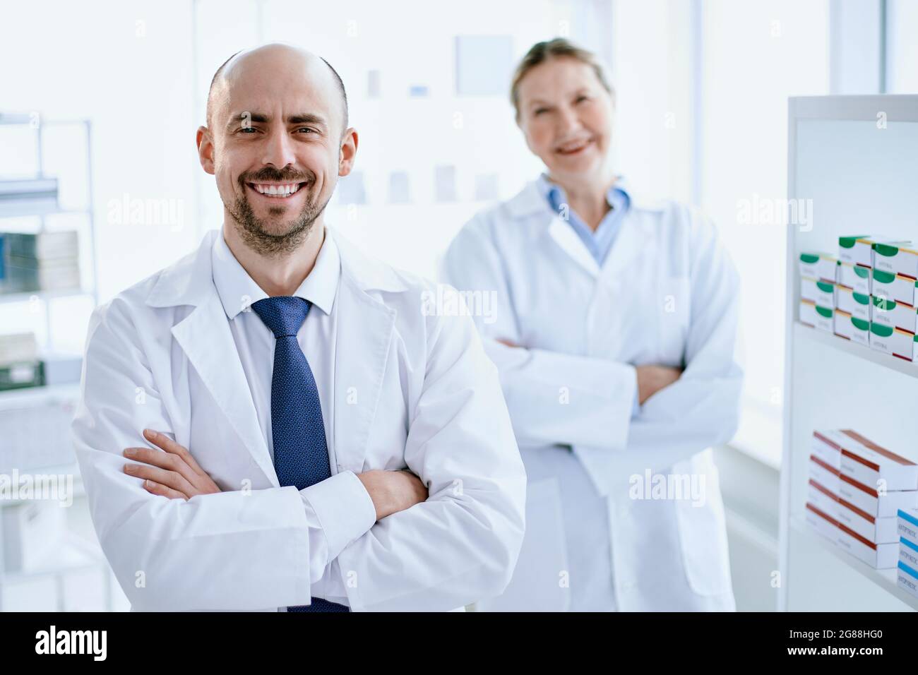 pharmacist and his assistant standing near the showcase with medicines