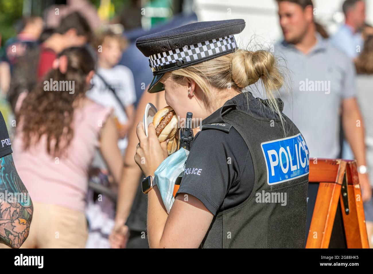 A police officer eating a hamburger at a crowded food and drink
