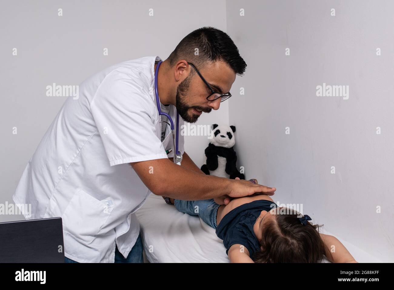 30-year-old Caucasian doctor examining his little patient, a 3-year-old girl. Stock Photo