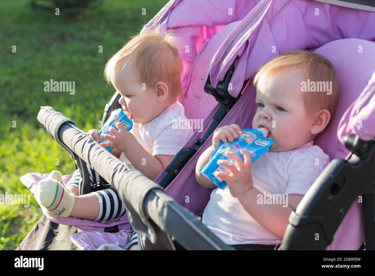 Portrait of hungry twin girls on street with mashed potatoes in their hands. Stock Photo