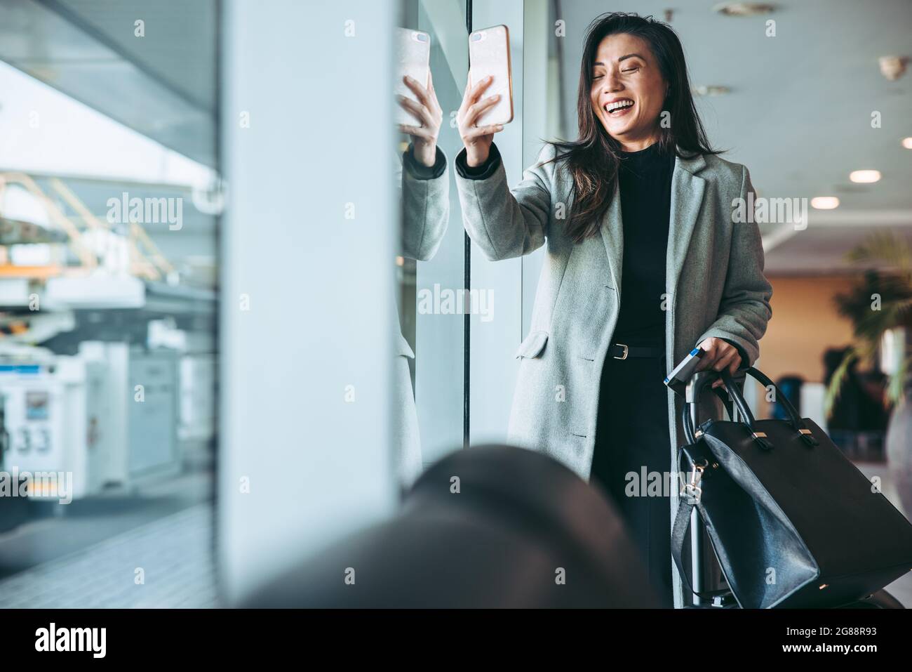 Happy businesswoman taking selfie at airport lounge. Female passenger ...