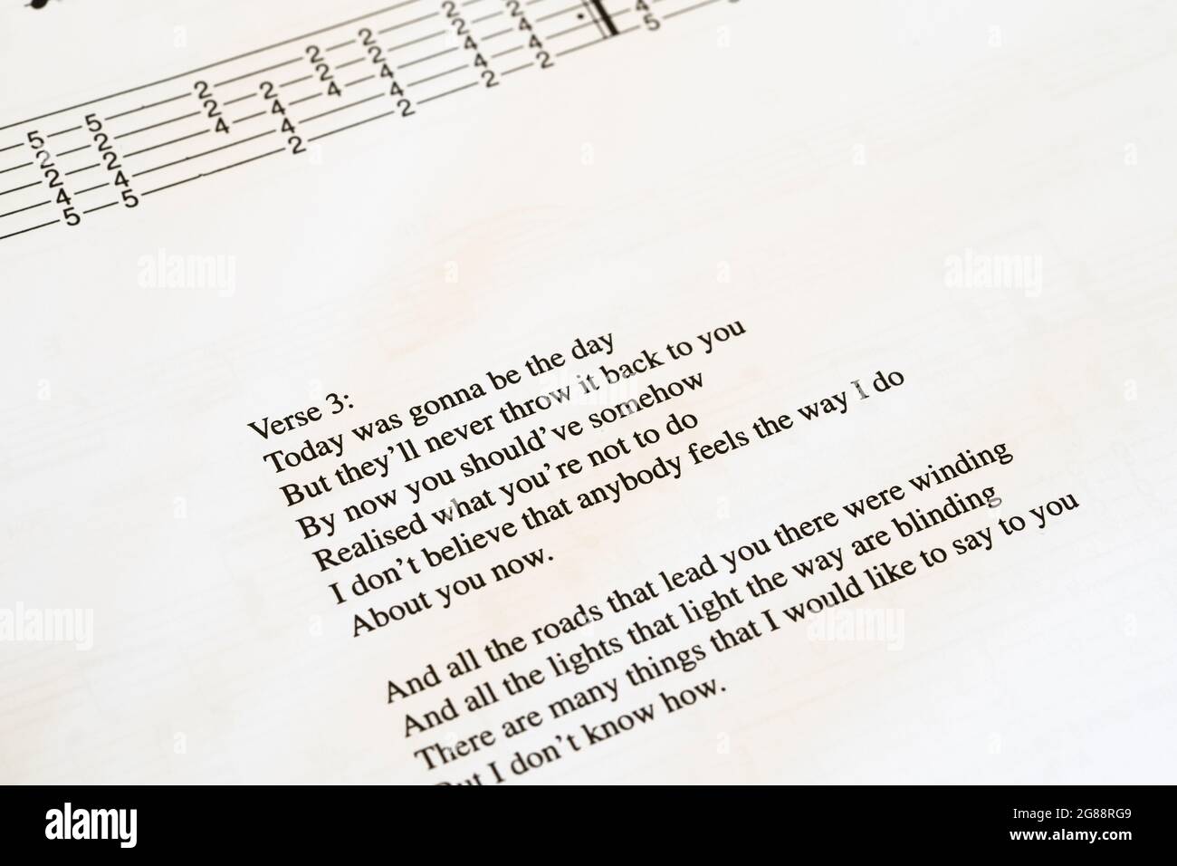 A guitar tab / tablature book showing a page with the lyrics for the Oasis song 