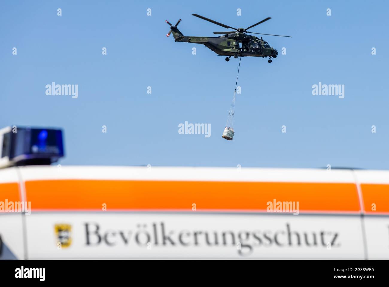 18 July 2021, Rhineland-Palatinate, Nürburg: A Bundeswehr NH90 helicopter flies over the Nürburgring with relief supplies. Massive rainfall has caused devastating flooding in Rhineland-Palatinate, and the Bundeswehr and aid organisations are on the scene with numerous helpers. Photo: Philipp von Ditfurth/dpa Stock Photo