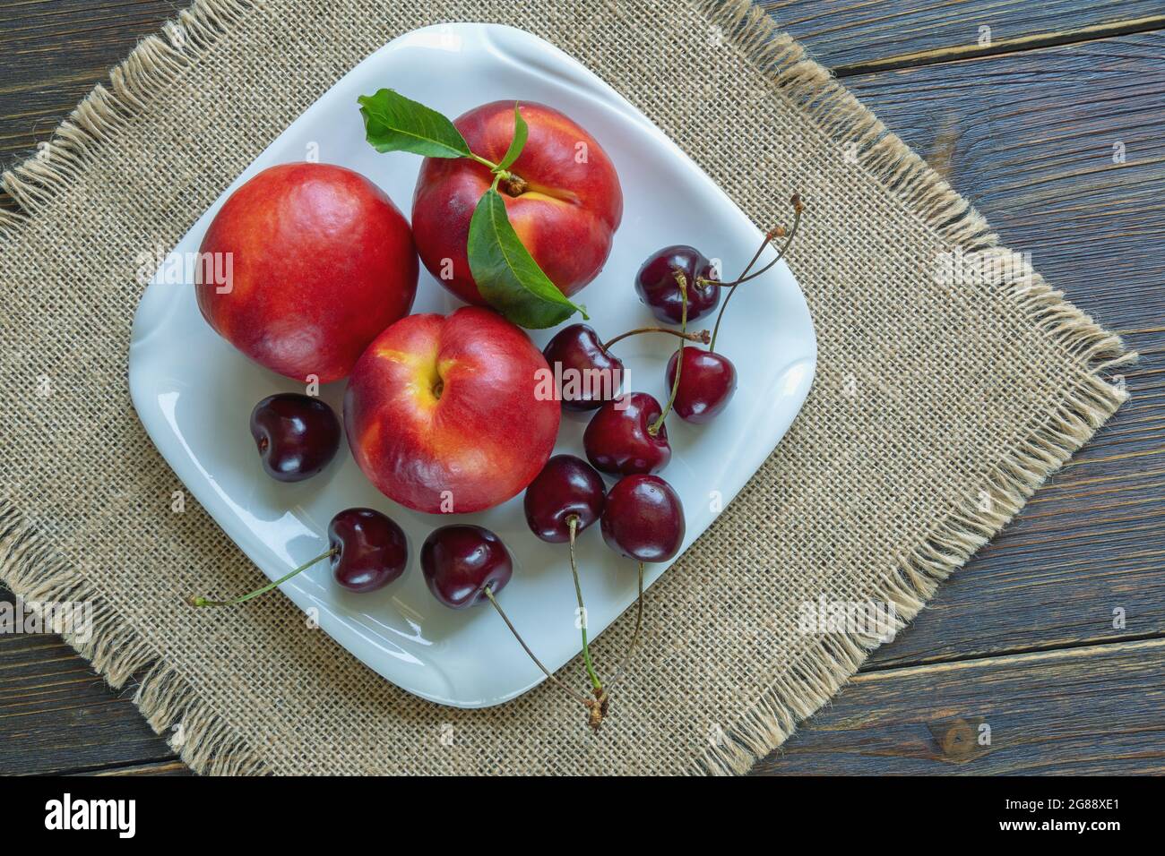 Fresh ripe cherries and nectarines on white plate. Rustic table. Flat lay Stock Photo