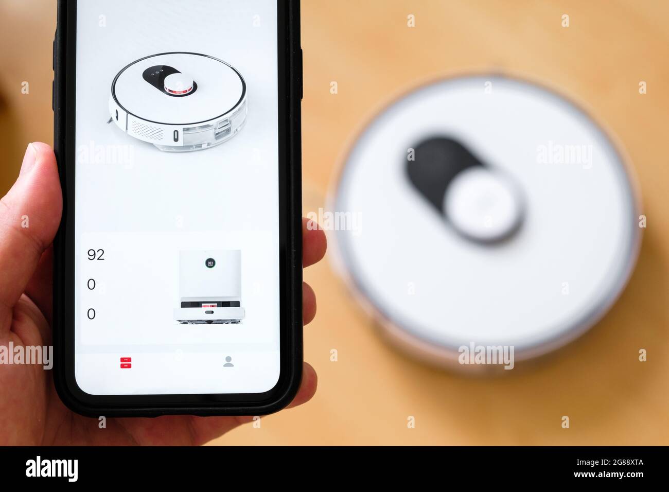Close up a mobile phone application for managing of robot vacuum cleaner in mans hand. Smart