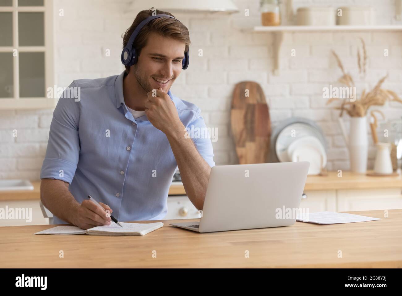 Confident young male in headset watching web course on pc Stock Photo
