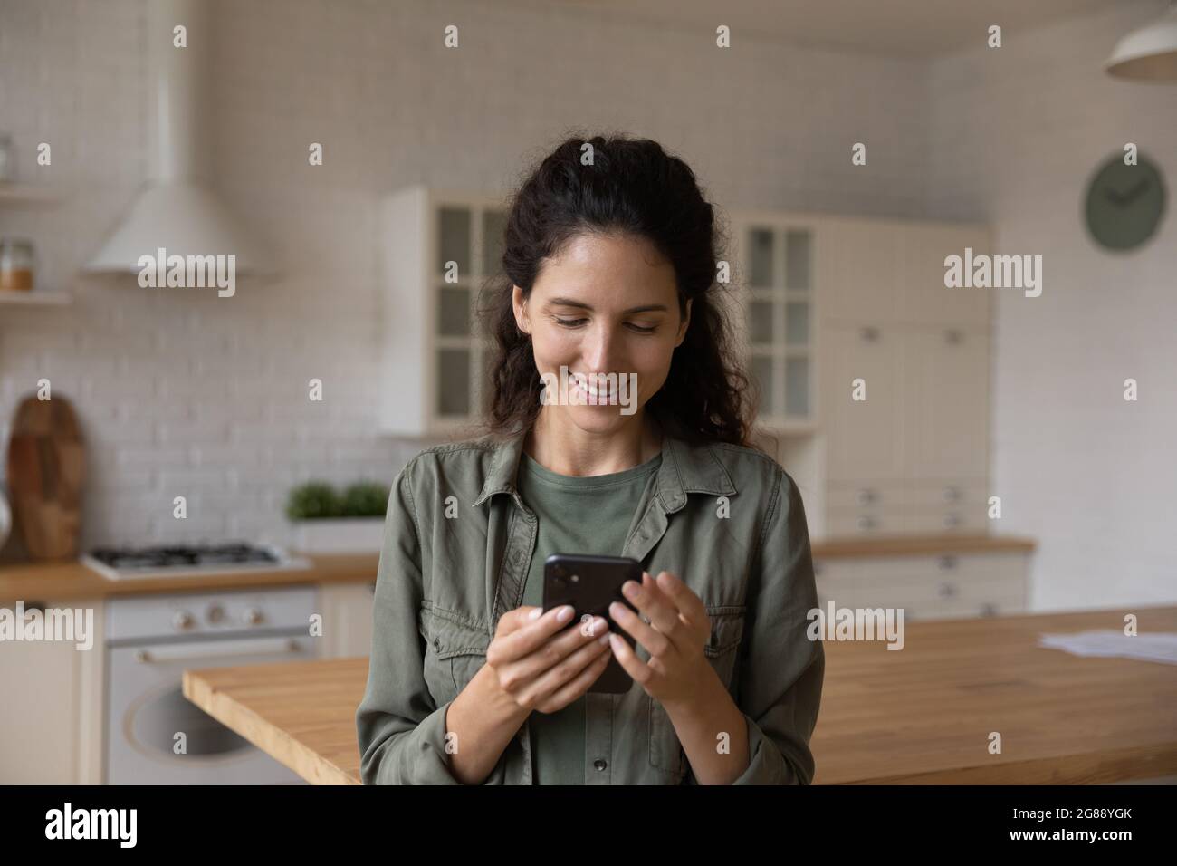 Young lady look at phone screen chat online at kitchen Stock Photo