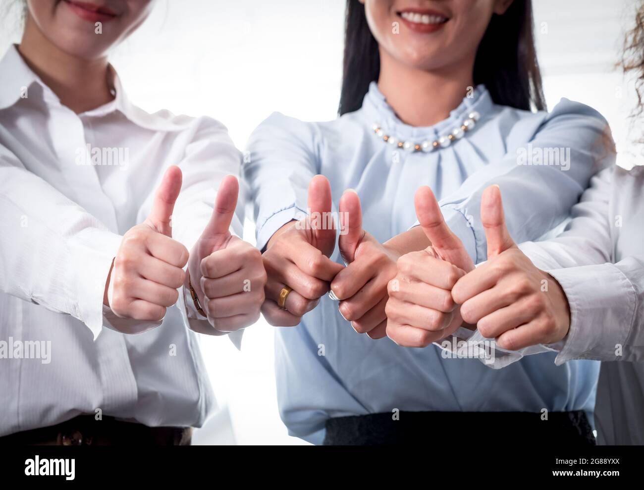 Three businesswoman partners show the gesture of thumps up in the modern office. Team Work Business Concept Stock Photo