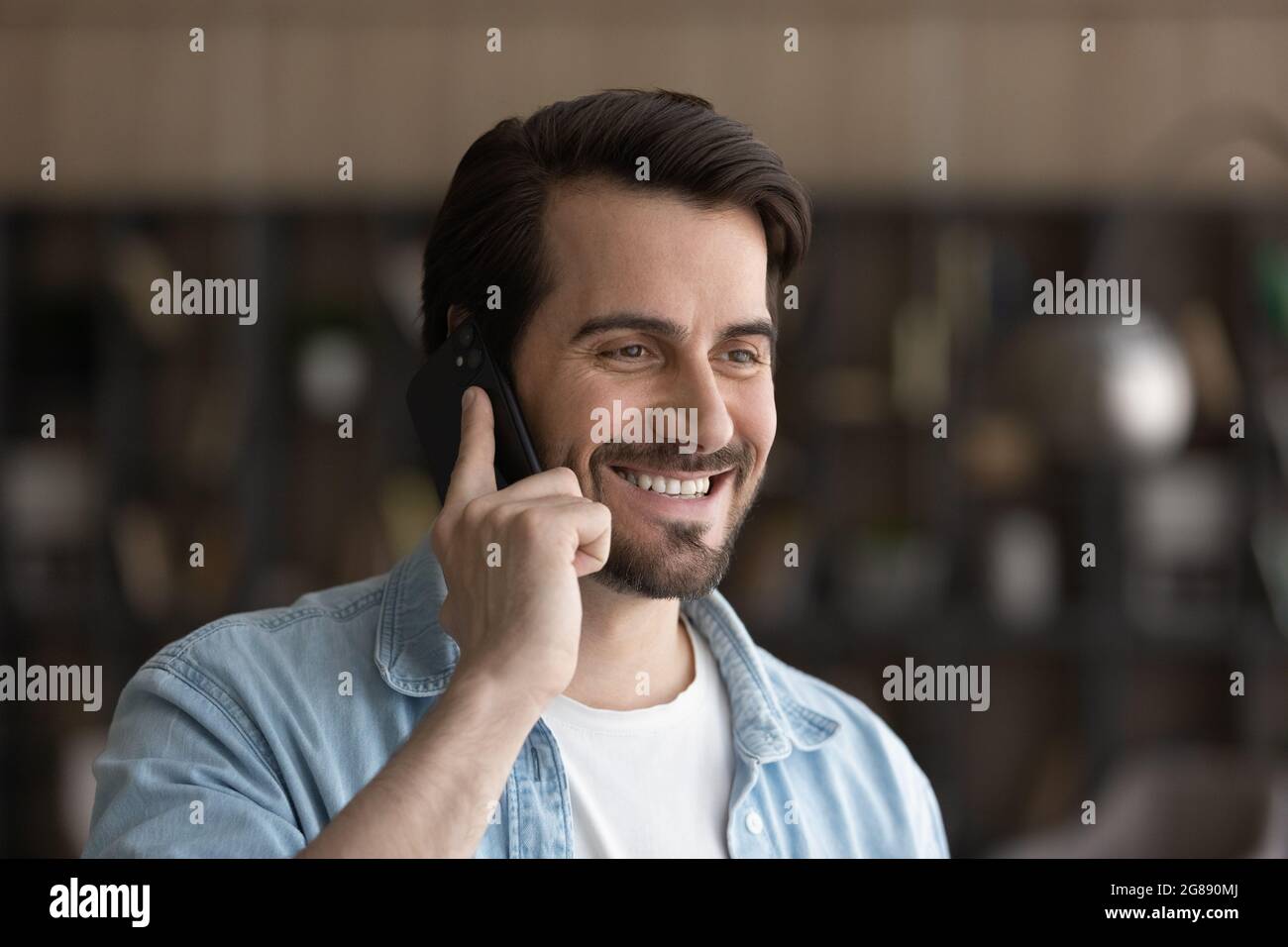 Sincere smiling young man holding telephone conversation. Stock Photo