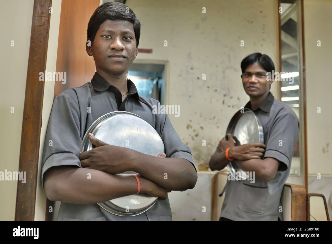 Two waiters in an Indian 'thali' restaurant in Mumbai, India, waiting for the day's first patrons Stock Photo