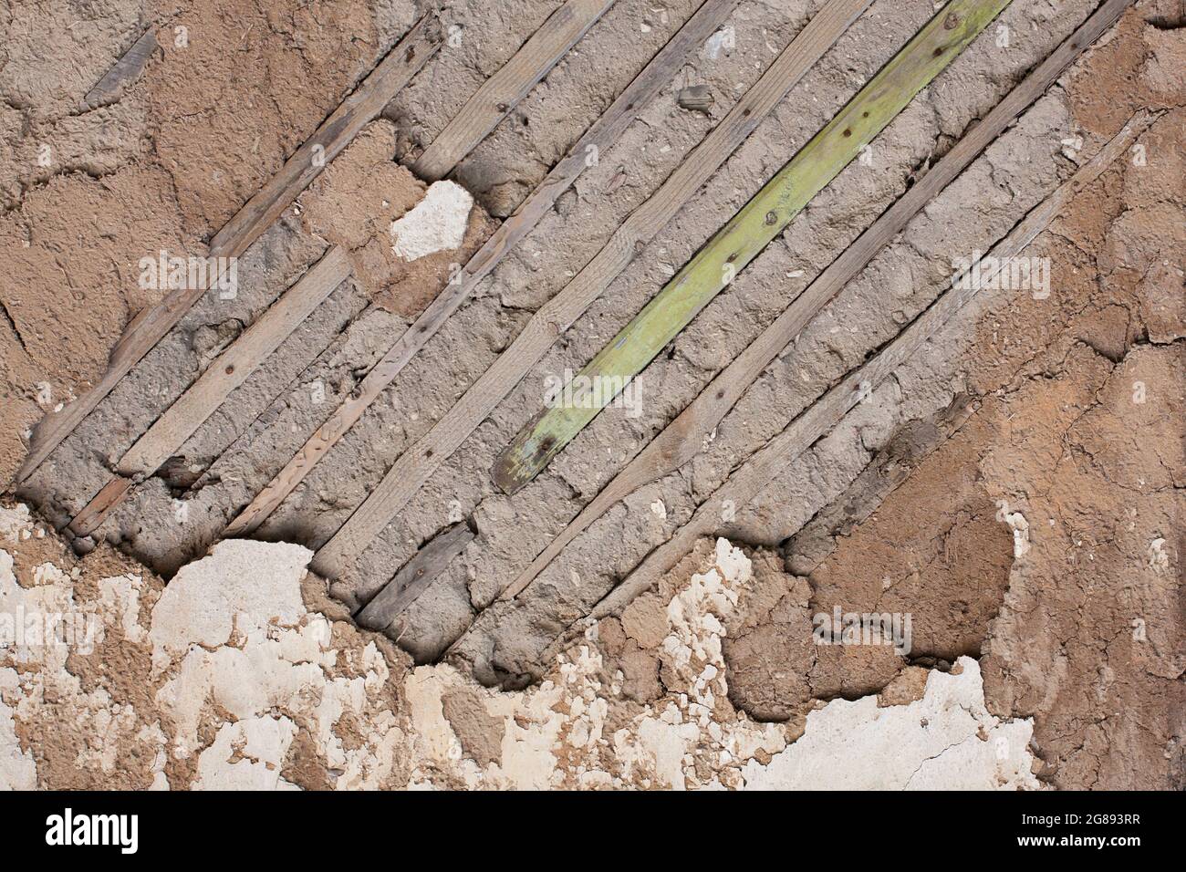 Fragment of an old destroyed wall with fallen off plaster and wooden lath in abandoned house. Close-up Stock Photo