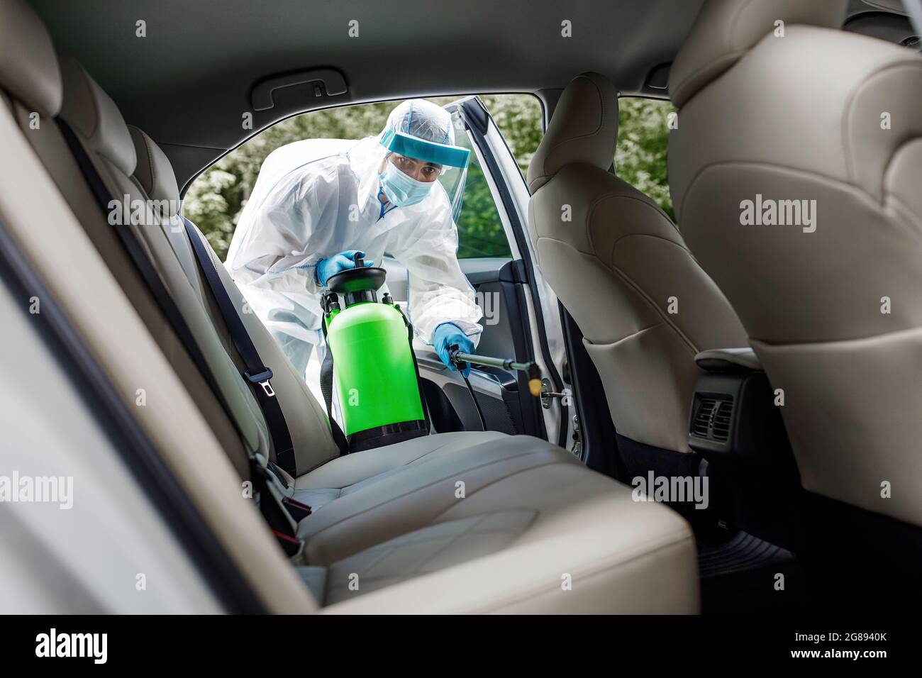 Specialist cleaner wearing hazmat suite, personal protective equipment PPE using chemical alcohol spray Stock Photo