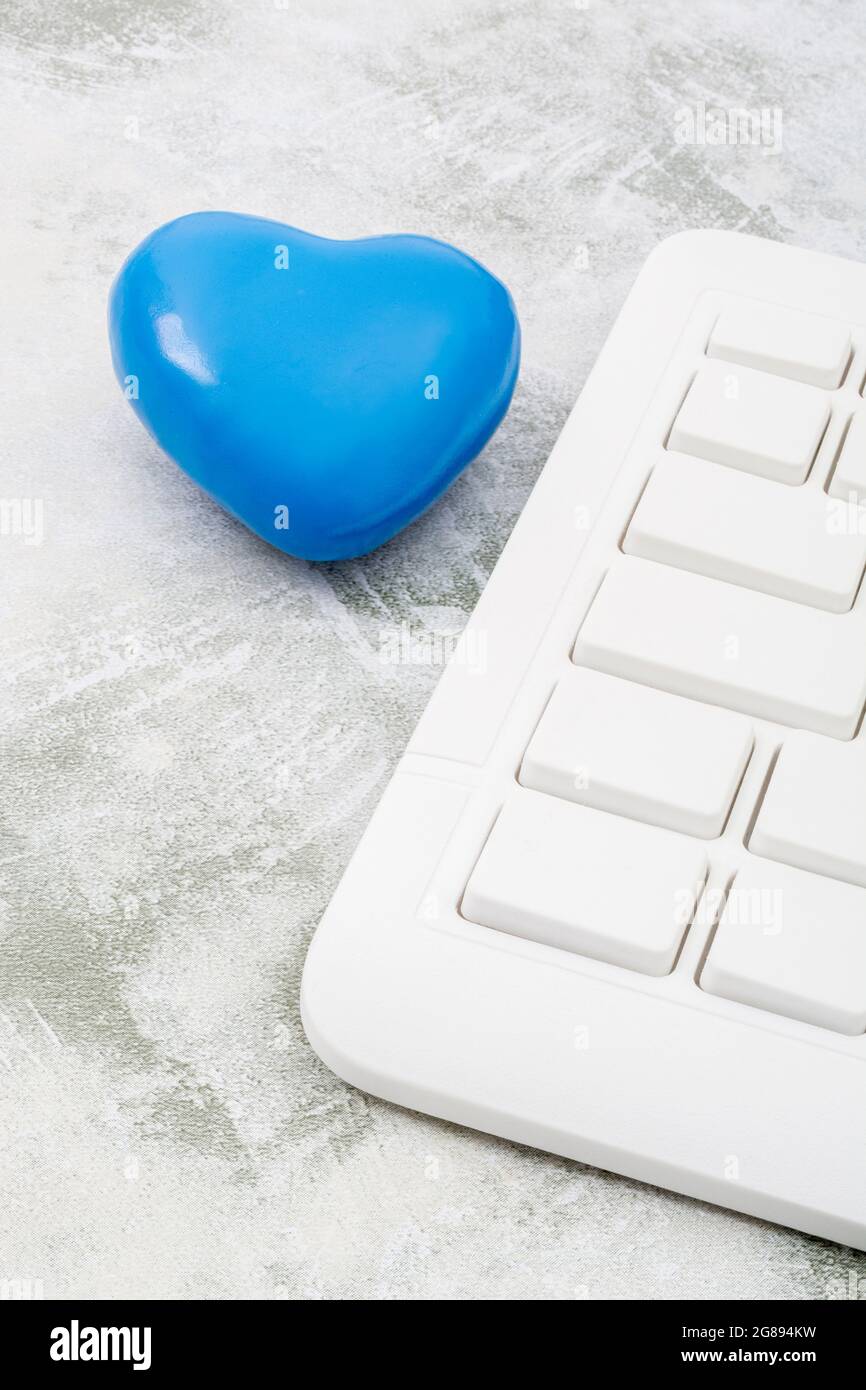 Blue heart + white Qwerty keyboard for Blue Monday, feeling gloomy / dispirited, poor office morale, being dumped online, Covid lockdown mental blues. Stock Photo