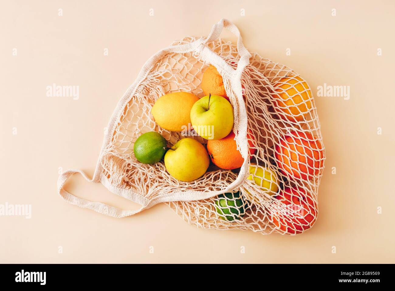 Mesh shopping bag with fresh fruits on light colored background. Zero waste, plastic free concept. Stock Photo
