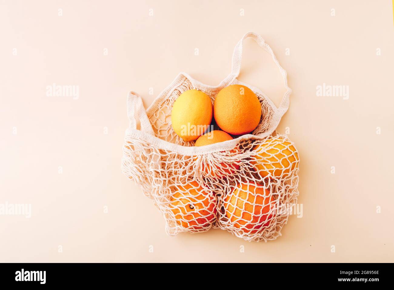 Mesh shopping bag with fresh fruits on light colored background. Zero waste, plastic free concept. Stock Photo