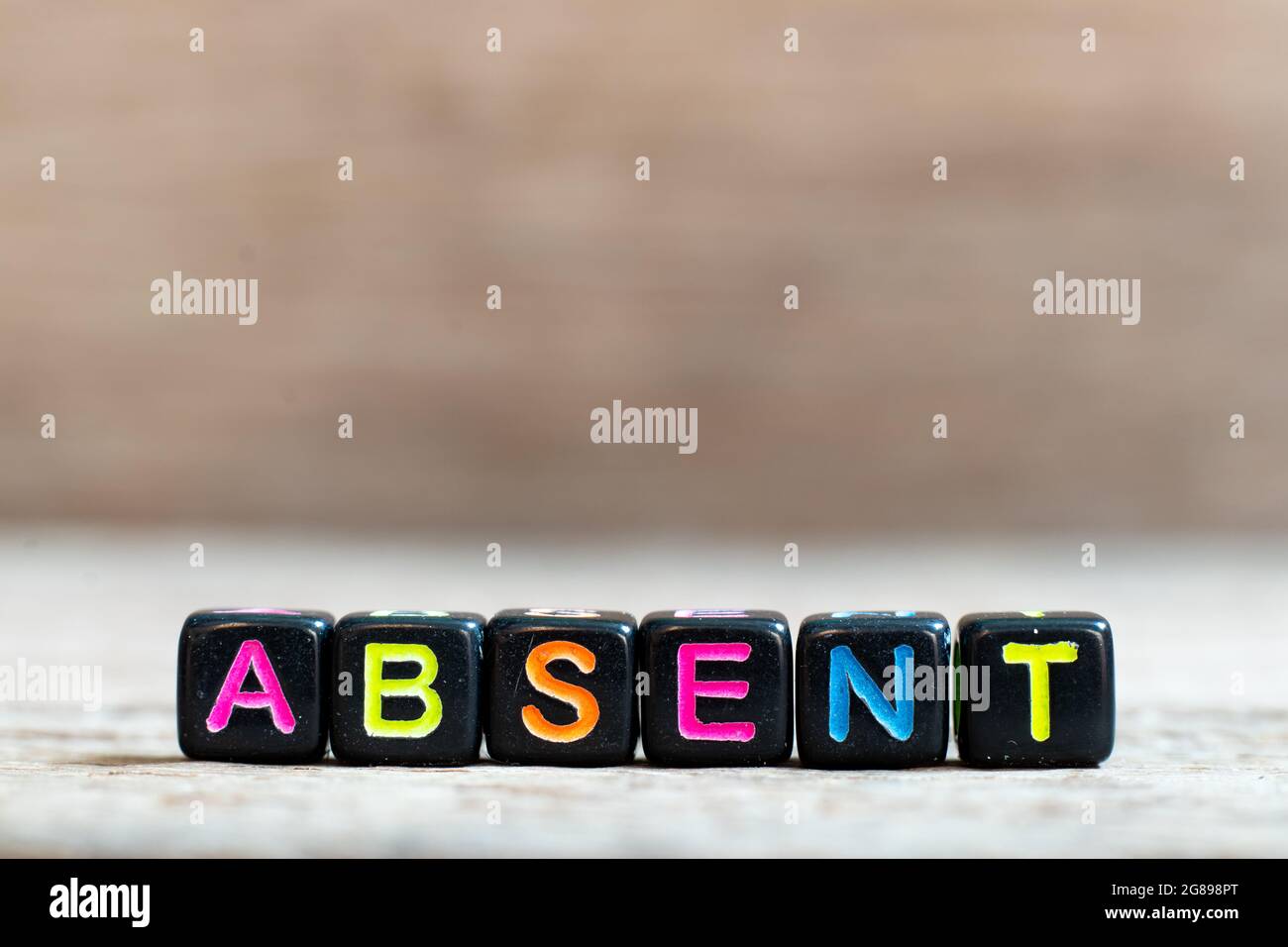 Black bead with color alphabet in word absent on wood background Stock ...