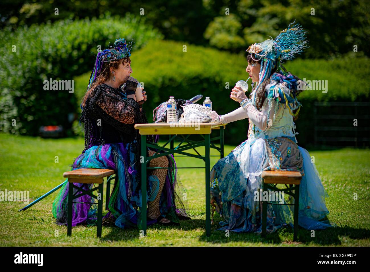 Friends Jane Brickwood, left, and Belinda Elkington, right, cool off with milkshake at Fantasy Forest, an open air festival at Sudeley Castle in Cheltenham, which remains the only private castle in England to have a queen buried within the grounds - Queen Katherine Parr, the last and surviving wife of King Henry VIII – who lived and died in the castle. Picture date: Sunday July 18, 2021. Stock Photo