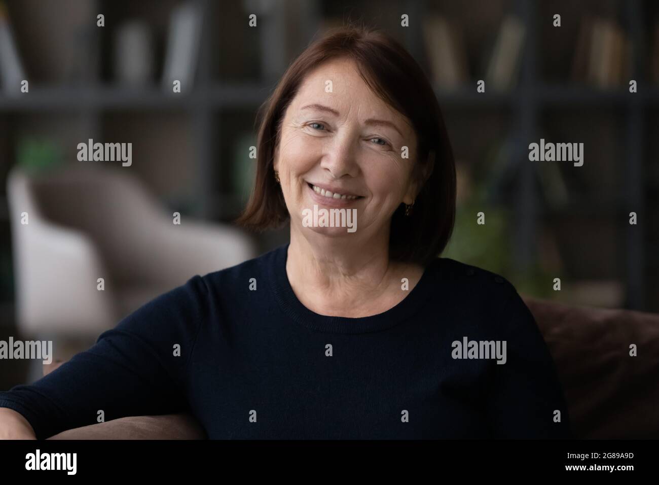 Happy senior mature woman sitting on couch at home Stock Photo - Alamy