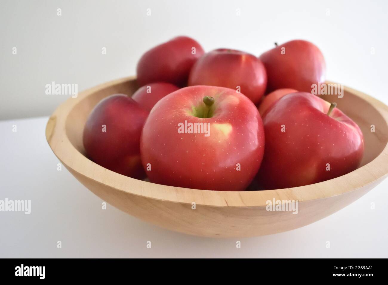 Red apples in a wooden bowl with gray white background Stock Photo