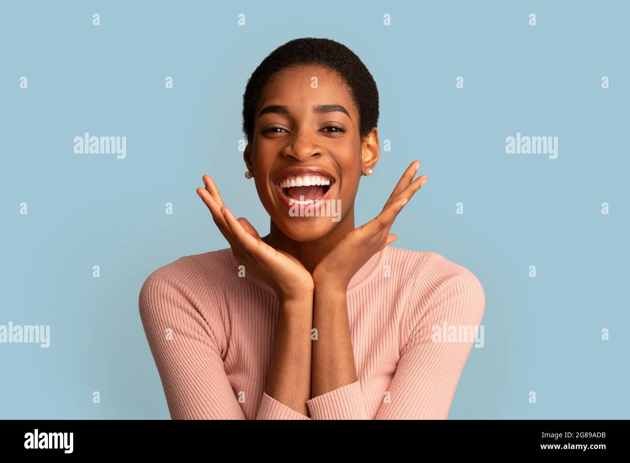 Happy Excitement. Joyful African Woman With Hands Near Face Laughing At Camera Stock Photo