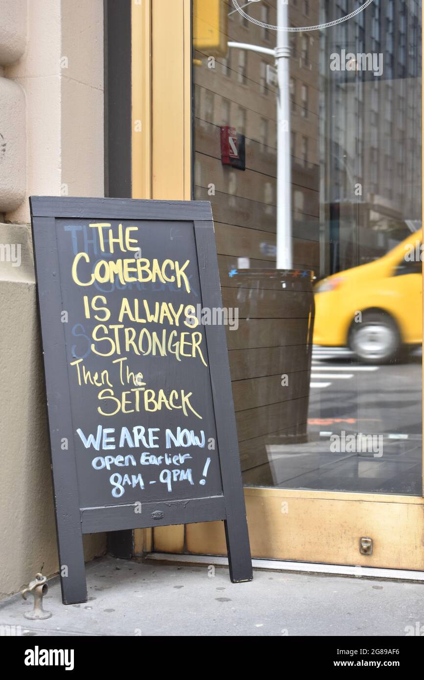 Blackboard sign leaning against glass door The Comeback Is Always Stronger Than The Setback with yellow cab in reflection, May 23, 2021, in  New York Stock Photo