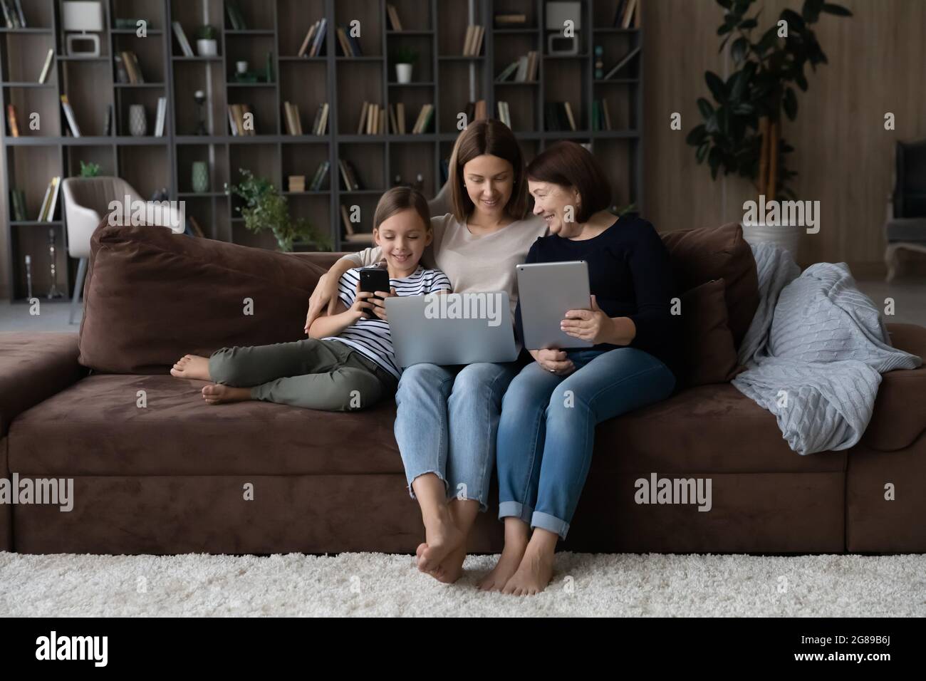 Three female generations of family relaxing on couch Stock Photo