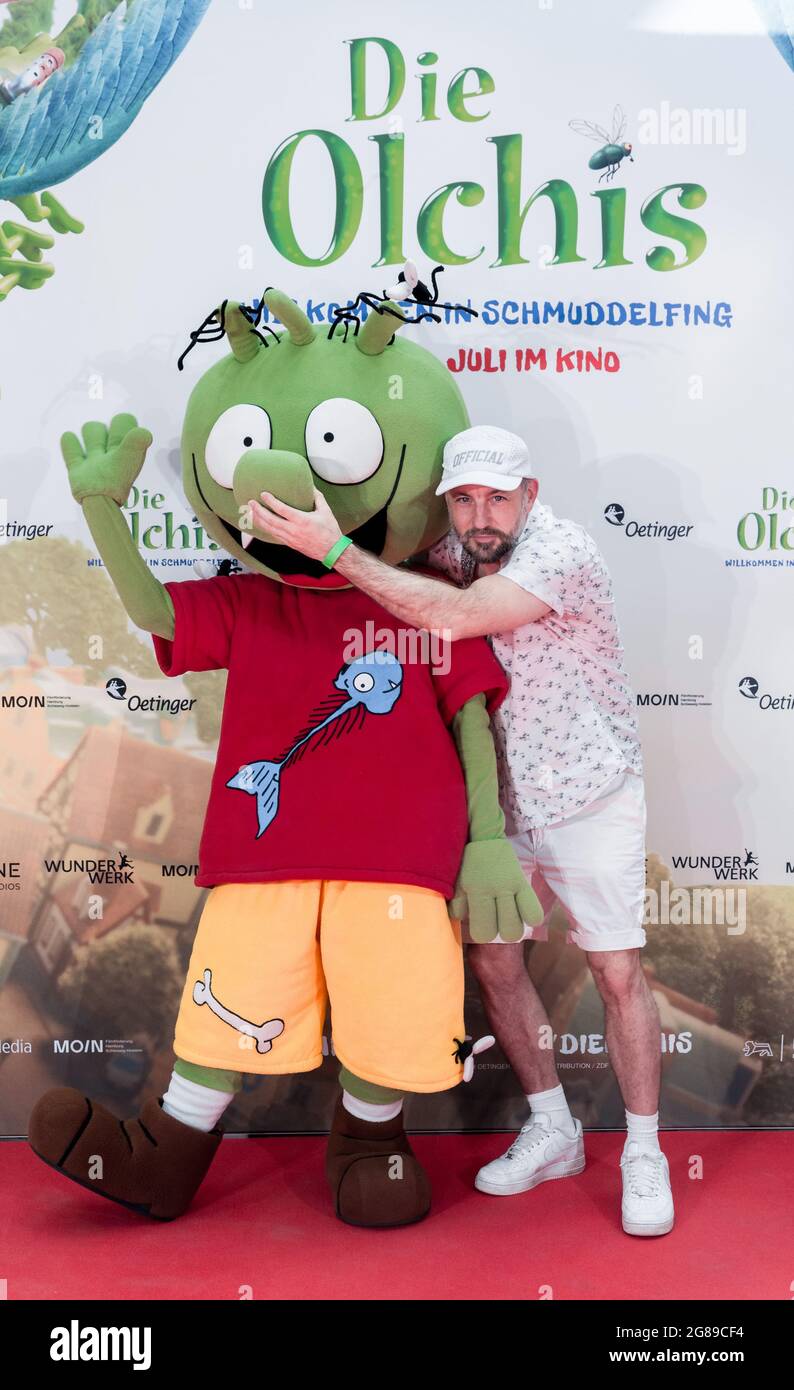 Hamburg, Germany. 18th July, 2021. Das Bo, rapper, author and interpreter of the title song, stands on the red carpet with an Olchis figure at the German premiere of the film 'Die Olchis - Willkommen in Schmuddelfing'. Credit: Markus Scholz/dpa/Alamy Live News Stock Photo